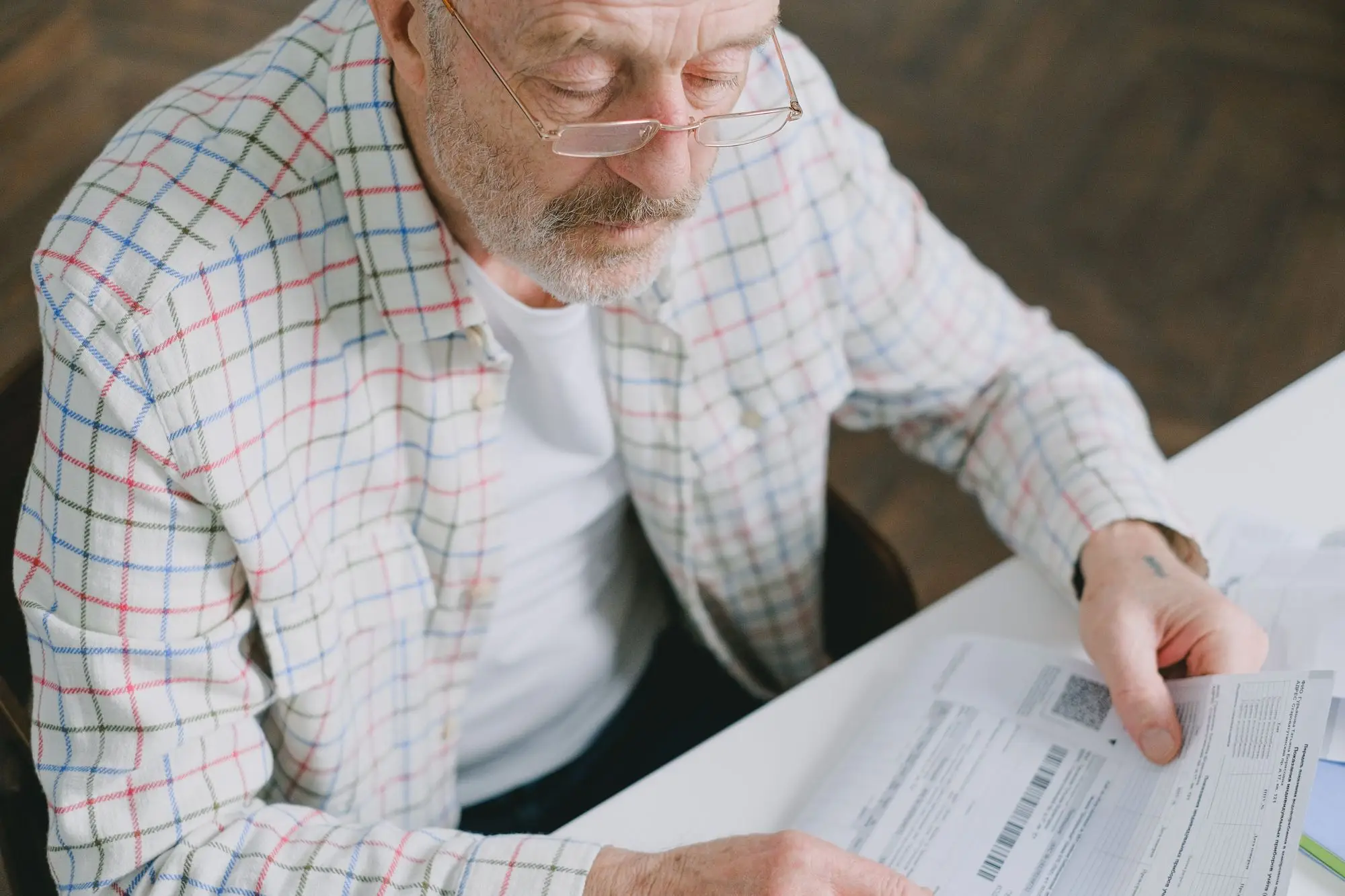 Older business owner in reading glasses going through his super fund statements at a desk